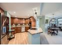 Well-lit kitchen featuring wood cabinets, stainless appliances, and an island with a countertop cooktop at 8100 E Union Ave # 614, Denver, CO 80237