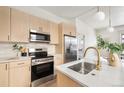 A modern kitchen is equipped with stainless steel appliances and features sleek, light wood cabinets and elegant hardware at 1470 Knox Ct, Denver, CO 80204