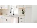 Modern kitchen with stainless steel dishwasher and white cabinets and backsplash at 930 S Lowell Blvd, Denver, CO 80219