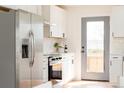 Modern kitchen features stainless steel refrigerator, white cabinets, and a glass door at 930 S Lowell Blvd, Denver, CO 80219
