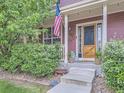 Inviting front porch with American flag, potted plants, and decorative accents at 8367 Devinney St, Arvada, CO 80005