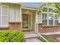 Close-up view of the front door with brick accents and well-maintained landscaping at 2980 W Long Dr # E, Littleton, CO 80120