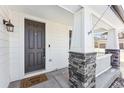 Inviting front porch featuring stone columns, a dark-colored front door, and a decorative welcome mat at 2548 Horsehound Pl, Castle Rock, CO 80104