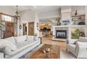 Open-concept living space with a fireplace, view into the kitchen, and hardwood floors at 1654 Muirfield Ln, Evergreen, CO 80439