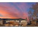 Ranch-style home with brick exterior, wood fence, and a beautiful sunset in the background at 12573 W 8Th Ave, Golden, CO 80401