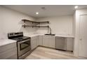 A well-lit kitchen features stainless steel appliances, open shelving and stone countertops at 201 S Monmouth Ave, Firestone, CO 80520