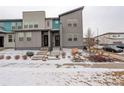 Modern townhome featuring clean architectural lines, a well-maintained yard, and inviting entryways in a snowy landscape at 16102 E 47Th Pl, Denver, CO 80239