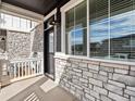 Inviting front porch with stone accents, classic lighting, and a large window at 6532 N Malaya St, Aurora, CO 80019