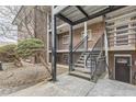 Exterior metal stairwell leading to apartments with brick facade and trimmed shrubbery in view at 6800 E Tennessee Ave # 111, Denver, CO 80224