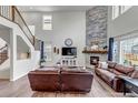 Open-concept living area with a stone fireplace, hardwood floors, and a staircase with iron railings at 697 Sundance Cir, Erie, CO 80516