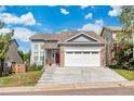 Two-story home featuring blue siding, mature trees and a two car garage at 12388 Jasmine St, Brighton, CO 80602