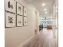 Hallway with wood floors, framed photos, and a view to the living area with natural light at 2144 Coyote Mint Dr, Monument, CO 80132