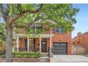 Charming red brick home featuring a cozy front porch and an attached garage, enhanced by mature trees at 2436 W Argyle Pl, Denver, CO 80211