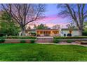 Large backyard featuring mature trees, tiered landscaping, and a covered patio with seating at 7900 Crest Dr, Lakewood, CO 80214