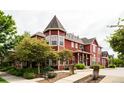Charming red townhome features unique architectural details, lush landscaping, and inviting curb appeal at 7777 E 23Rd Ave # 1202, Denver, CO 80238
