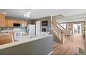 Open kitchen features wood cabinets, white appliances, and easy access to the staircase and living room at 7841 S Kalispell Cir, Englewood, CO 80112