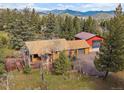 An aerial view capturing the home's setting among mature trees with mountain views in the background at 7754 Swaps Trl, Evergreen, CO 80439