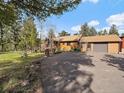 The front of the house is nicely landscaped with a long driveway surrounded by mature trees and shrubs at 7754 Swaps Trl, Evergreen, CO 80439