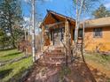 Charming covered front porch featuring stone pillars and brick steps to the front door at 7754 Swaps Trl, Evergreen, CO 80439