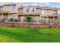 Inviting townhomes with manicured lawn, brick retaining wall, and black metal fencing at 1818 S Quebec Way # 4, Denver, CO 80231