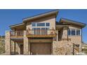 Contemporary home with a stone and wood exterior, a two-car garage, and a lovely deck at 5721 Country Club Dr, Larkspur, CO 80118