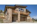 Stylish two-story house boasting stone accents, a deck, an attached two-car garage, and wood siding at 5721 Country Club Dr, Larkspur, CO 80118