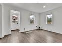 Bright living room featuring wood-look flooring, fresh white walls, and plenty of natural light from two windows and front door at 1000 S Perry St, Denver, CO 80219