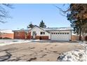 Ranch style home with a white garage door and snowy driveway at 420 Racine St, Aurora, CO 80011