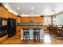 Spacious kitchen featuring wood cabinets, a central island with barstool seating, and modern black appliances at 2828 Shadow Dance Dr, Castle Rock, CO 80109