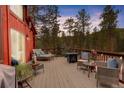 Inviting outdoor deck with comfortable lounge furniture, a fire pit, and scenic views of the surrounding trees at 6997 S Columbine Rd, Evergreen, CO 80439