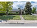 Charming single-story home featuring a well-manicured lawn and chain-link fence at 1099 Wheeling St, Aurora, CO 80011