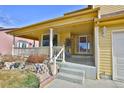 Covered front porch with white railings, columns and concrete steps to the front door at 288 Dover Ct, Broomfield, CO 80020