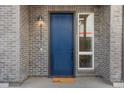 Front door of a brick townhouse with a blue painted door, modern light, and a side window at 5173 Vivian St, Wheat Ridge, CO 80033