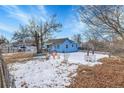 Spacious backyard with mature trees and a partially snow-covered lawn at 7111 Monaco St, Commerce City, CO 80022