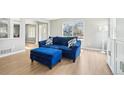 Inviting living room with light-colored wood floors, a large window, and a plush blue sofa with ottoman at 6565 W 99Th Ave, Broomfield, CO 80021