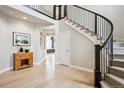 Grand foyer with hardwood floors, curved staircase with iron railing, and view of adjacent living spaces at 16272 W 95Th Ln, Arvada, CO 80007