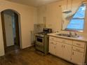 Vintage kitchen with classic appliances, double sink, and hardwood floors with arched door frame at 4209 Perry St, Denver, CO 80212