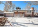 Brick ranch home with attached garage, snowy yard, and trees at 1859 S Saulsbury Ct, Lakewood, CO 80232