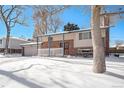 Brick ranch home with attached garage, snowy yard, and trees at 1859 S Saulsbury Ct, Lakewood, CO 80232