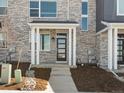 Welcoming front entrance featuring a modern black door, white pillars, and tidy landscaping at 22360 E 8Th Ave, Aurora, CO 80018