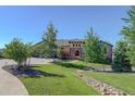 Charming front exterior with stone facade, two-car garage, and lush landscaping with a rock-lined stream bed at 4822 Bandera Pl, Parker, CO 80134