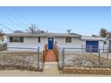 Charming home with ramp, blue door and partial chain link fenced yard at 621 Campo St, Denver, CO 80221