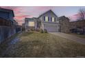 Charming two-story home with a well-maintained lawn and attached two-car garage at dusk at 16149 Peregrine Dr, Parker, CO 80134