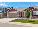 Inviting home exterior with a neatly kept lawn, two-car garage, and appealing stone veneer details at 11129 Paradise Ln, Firestone, CO 80504