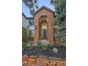 Beautifully landscaped front entrance highlighting brick archway, lighting, and lush greenery at 10125 Quarry Hill Pl, Parker, CO 80134