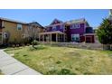 Spacious backyard featuring a lush green lawn, picket fence, and a two-story purple home at 8335 E 22Nd Ave, Denver, CO 80238
