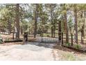 Gated driveway entrance flanked by wood posts and lush landscaping, offering privacy and charm at 5030 Cedar Way, Elizabeth, CO 80107