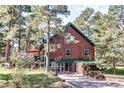 A-frame home has wood siding and a green metal roof nestled among trees, with a stone retaining wall at 5030 Cedar Way, Elizabeth, CO 80107