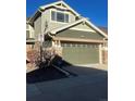 Two-car garage featuring a green door, stone accents, and visible house number at 15063 E Crestridge Dr, Centennial, CO 80015