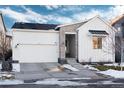 White two-story house with stone accents and a two-car garage, snowy landscape at 6437 Saddlesmith St, Castle Pines, CO 80108